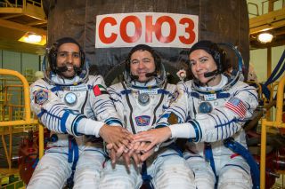 United Arab Emirates astronaut Hazza Al Mansouri (left) and Expedition 61 crewmates Oleg Skripochka (center) of Russia and Jessica Meir of NASA post for a crew portrait with their Soyuz MS-15 spacecraft ahead of a Sept. 25, 2019 launch.