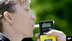 California Highway Patrol Sgt. Jaimi Kenyon blows into a breathalyzer held by Sacramento Police Corporal Luke Moseley during a demonstration of devices used to test drivers suspected of impaired driving Wednesday, May 10, 2017, in Sacramento, Calif. (AP)