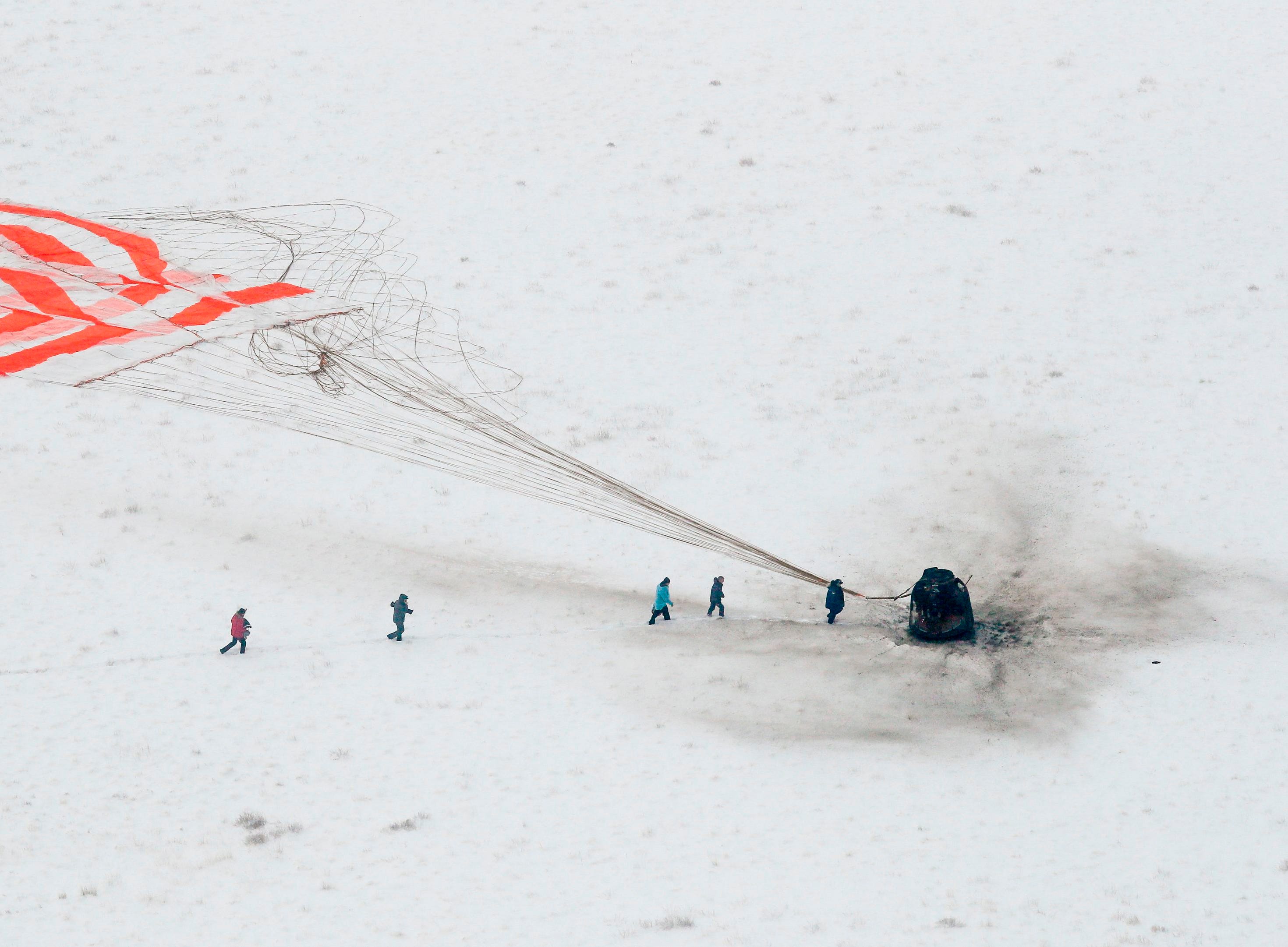 A search and rescue team approaches the Soyuz MS-09 capsule carrying the International Space Station crew after its landing in a remote area outside the town of Dzhezkazgan Kazakhstan, Dec. 20, 2018. 