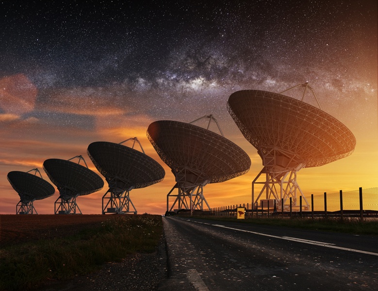 Row of five giant radio telescopes with Milky Way stretching above them.