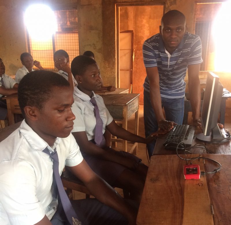 Young men looking at a small red box on a table.