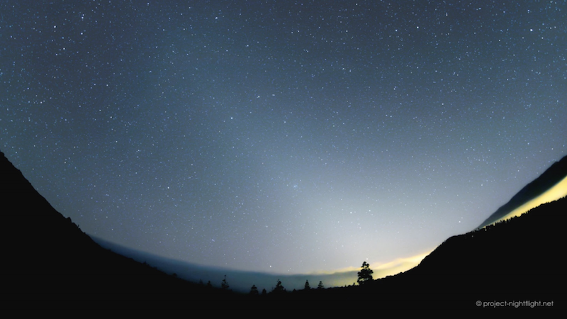 Twilight sky over panoramic horizon with long cone of light from sunset location.