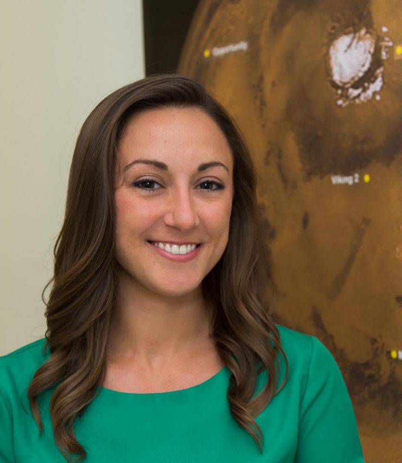 Smiling woman standing in front of poster on wall.