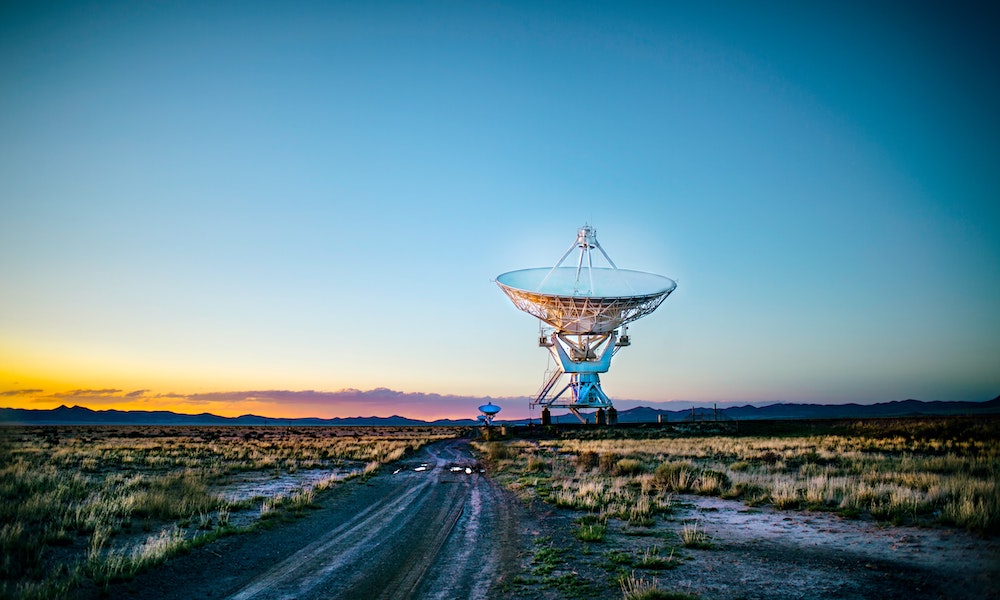 The Very Large Array radio telescope system in New Mexico, against the sky at sunset.