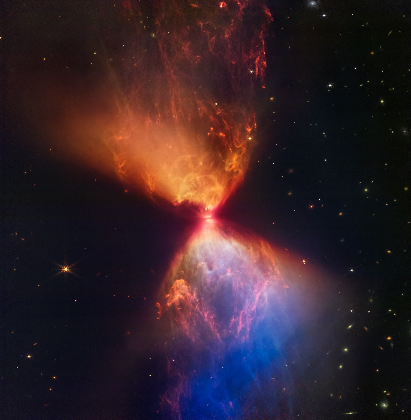 Clouds colored blue and orange in this representative-color infrared image, outline cavities created as material shoots away from the protostar and collides with surrounding matter. The colors themselves are due to layers of dust between Webb and the clouds. The blue areas are where the dust is thinnest. The thicker the layer of dust, the less blue light is able to escape, creating pockets of orange.